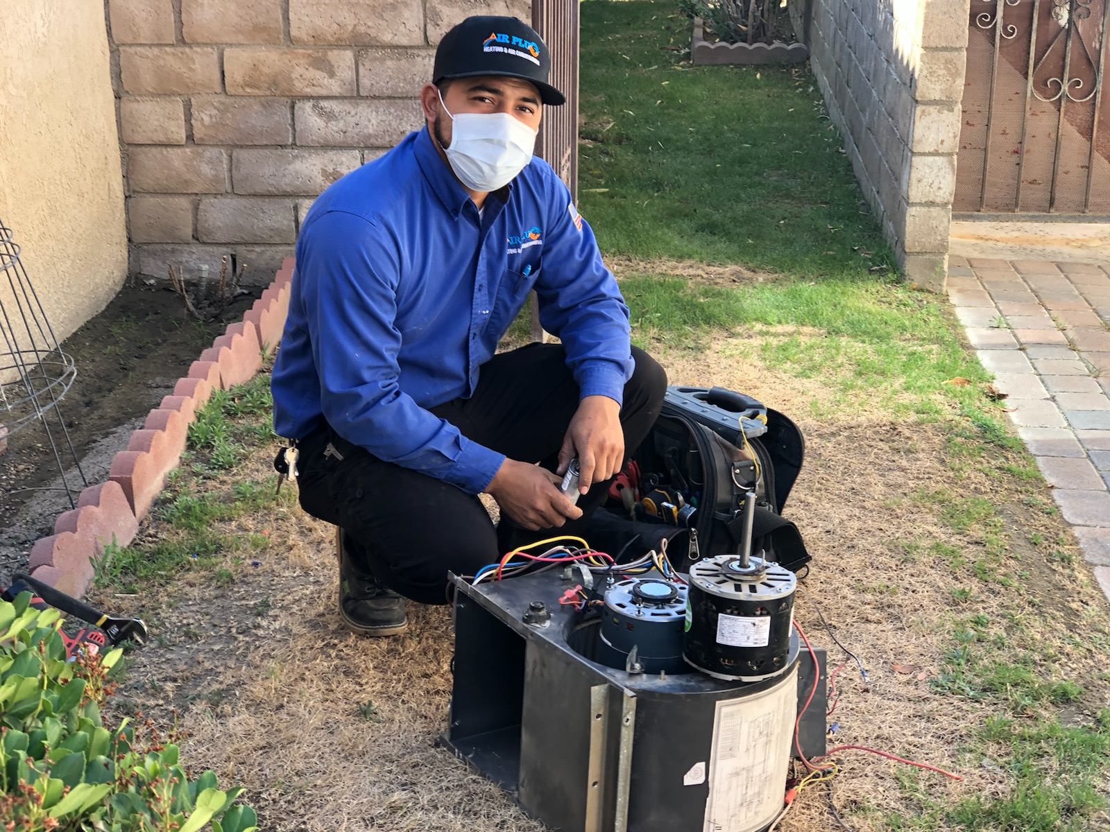 Air Plus technician servicing a blower motor during an HVAC repair visit