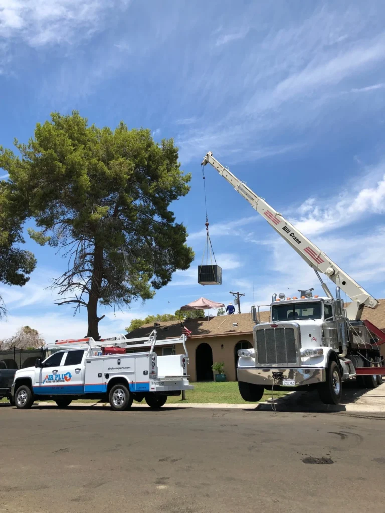 Crane setting a packaged HVAC unit on a residential rooftop